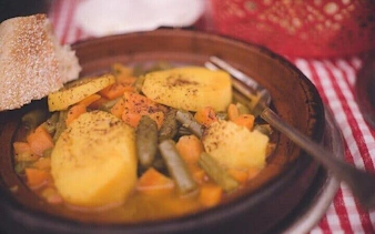 Moroccan vegetable tagine with bread on a striped tablecloth during Essaouira cooking class.