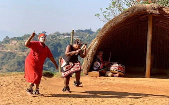 Traditional Zulu dancers performing near a hut in Durban, South Africa.