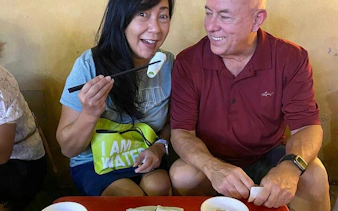 Couple enjoying street food on Hanoi After Dark Motorbike Tour.