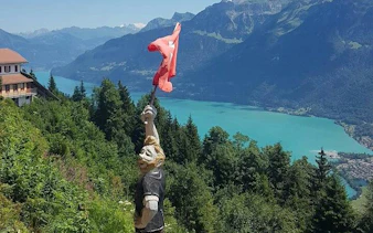 Statue holding Swiss flag overlooking Lake Brienz in Interlaken region, Switzerland.