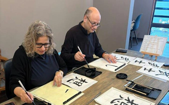 Participants practicing Japanese calligraphy with brushes in Yamanashi class near Mt. Fuji.