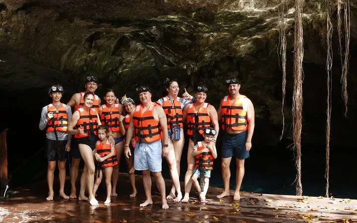 Group preparing for snorkeling tour in cenote, wearing life vests and goggles, Mexico.