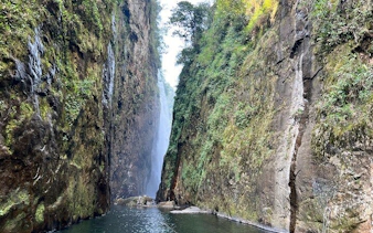 Dragon Waterfall between lush cliffs on Sapa motorbike tour route.