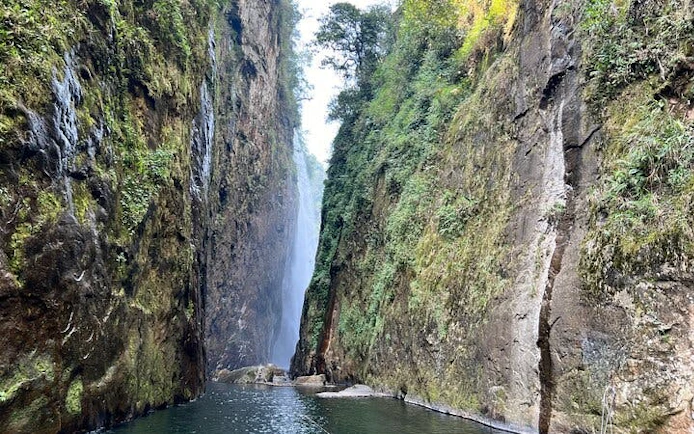 Dragon Waterfall between lush cliffs on Sapa motorbike tour route.