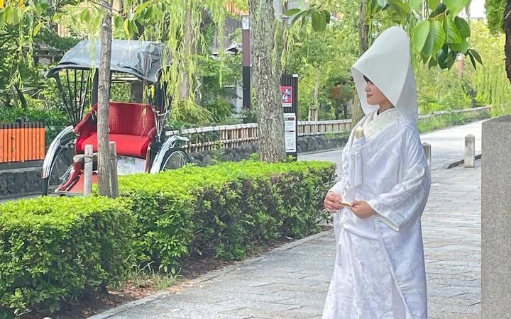 Geisha in traditional attire walking in Kyoto's Gion district with a rickshaw in the background.