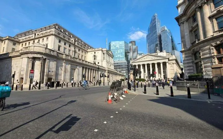 London street view near Bank of England with cyclists and pedestrians.