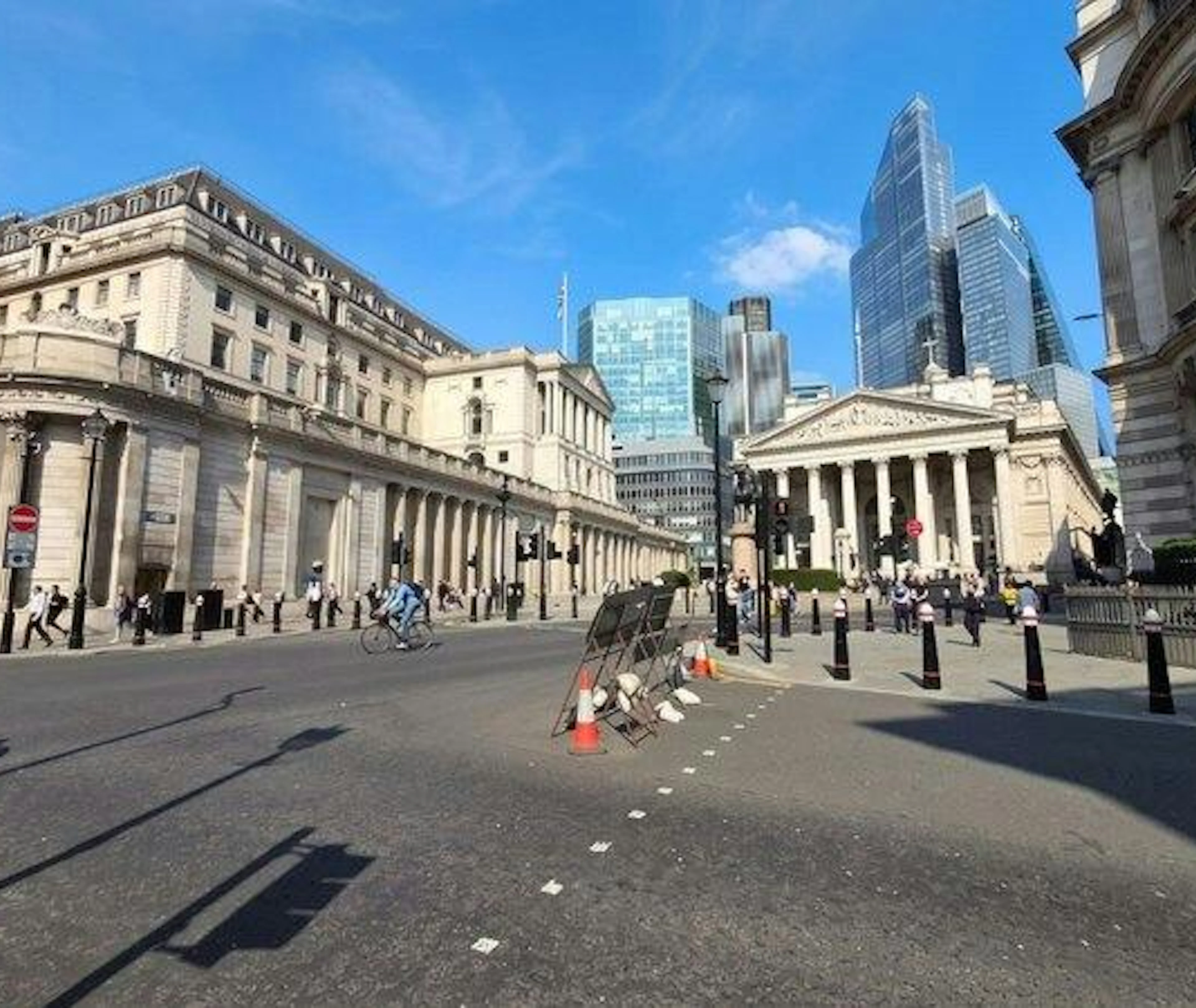 London street view near Bank of England with cyclists and pedestrians.