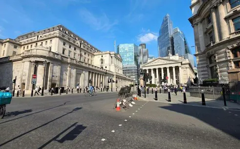 London street view near Bank of England with cyclists and pedestrians.