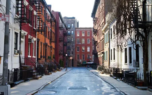 Manhattan street with historic brownstones, part of self-guided city exploration game.