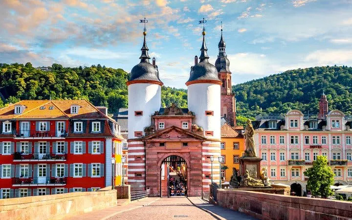 Heidelberg Old Bridge gate with cityscape and hills in background on self-guided walking tour.