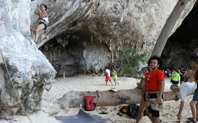 Rock climbers at Railay Beach, Krabi, scaling limestone cliffs with safety gear.