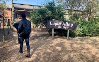 Man walking towards Eagle Alley sign at Natal Lion Park, Durban.
