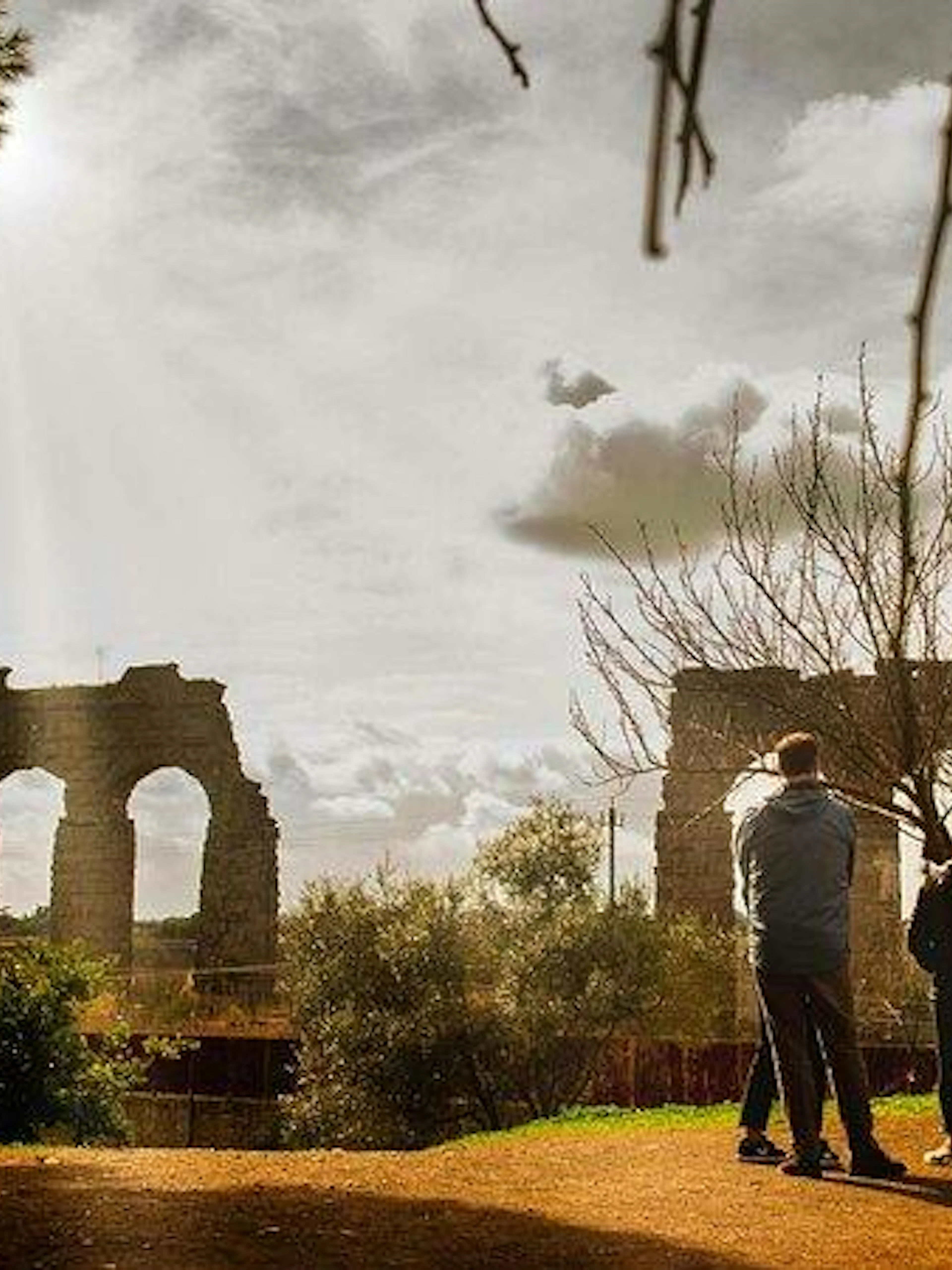Group of people on a guided tour near ancient Roman aqueducts on the Appian Way, Rome.