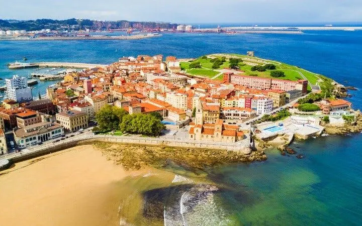 Aerial view of Gijón coastline with historic buildings and beach, Spain.