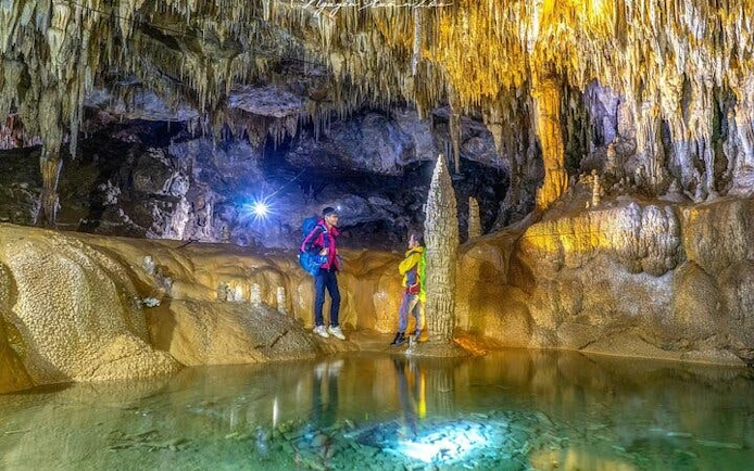 Visitors exploring Pusamcap Cave with stalactites and stalagmites in Sapa motorbike tour.