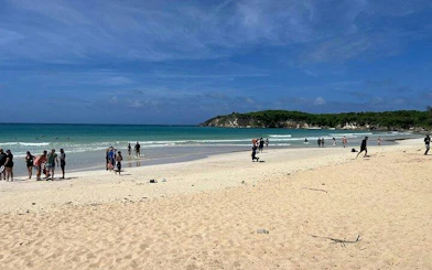 Beachgoers enjoying Macao Beach in Punta Cana with clear blue water and distant greenery.