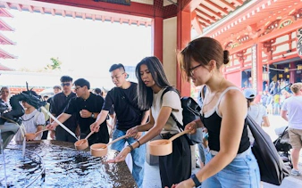 Visitors using ladles at Senso-ji Temple purification fountain during Tokyo Asakusa walking tour.