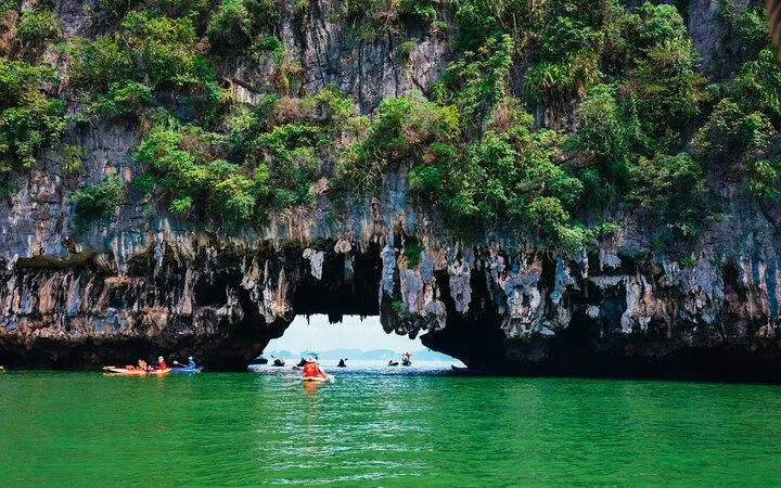 Canoes exploring caves in Phang Nga Bay, Phuket, during twilight tour.