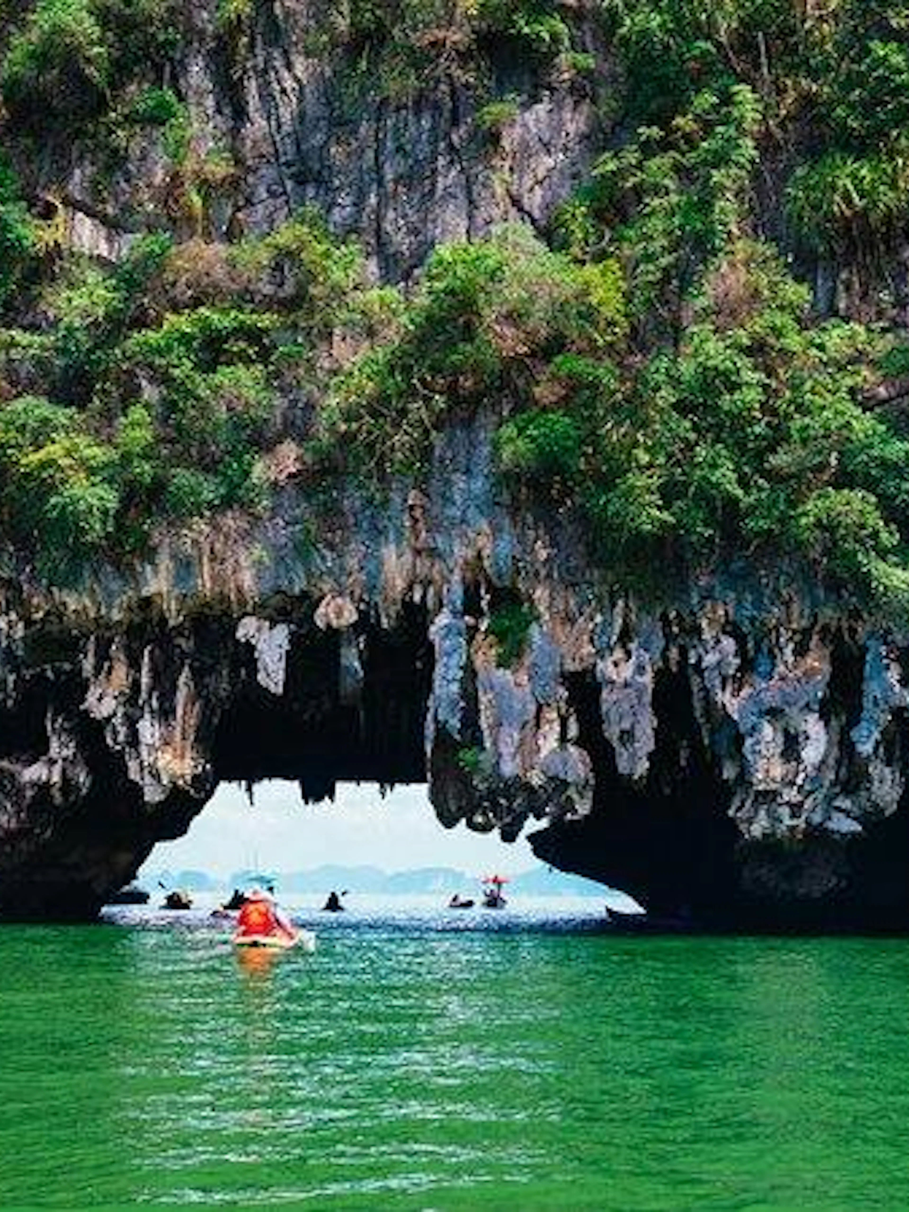 Canoes exploring caves in Phang Nga Bay, Phuket, during twilight tour.