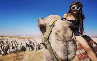 Camel ride in Cappadocia with scenic rock formations in the background.