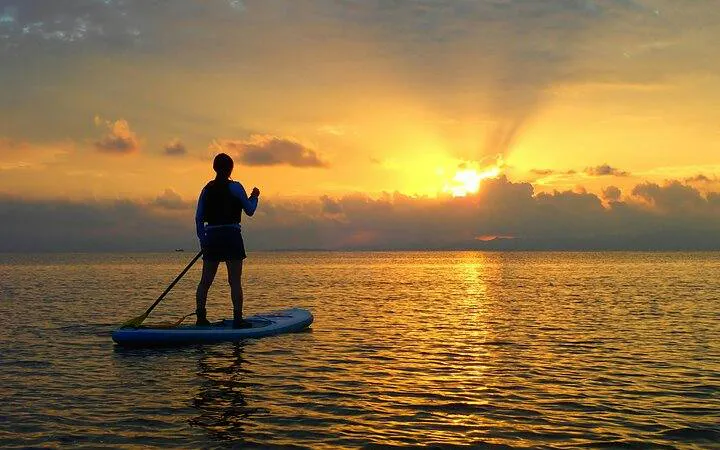 Person paddleboarding at sunset on Ishigaki Island, Okinawa.