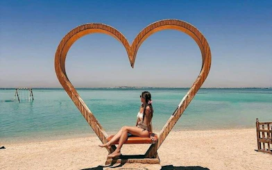 Woman sitting on heart-shaped bench by the sea on Hula Hula Island, Hurghada.