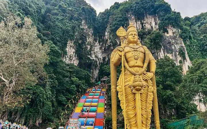 Golden Lord Murugan statue at Batu Caves entrance with colorful steps, Kuala Lumpur.