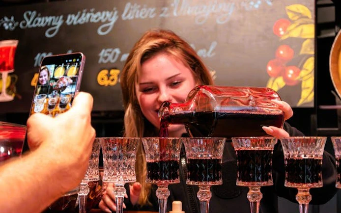 Pouring cherry liqueur into glasses during Bratislava food tour.