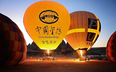 Hot air balloons preparing for sunrise flight over Cappadocia landscape.