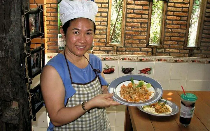 Chiang Mai cooking class participant holding a plate of prepared Thai dish at Baan Hongnual.