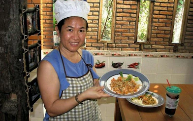 Chiang Mai cooking class participant holding a plate of prepared Thai dish at Baan Hongnual.
