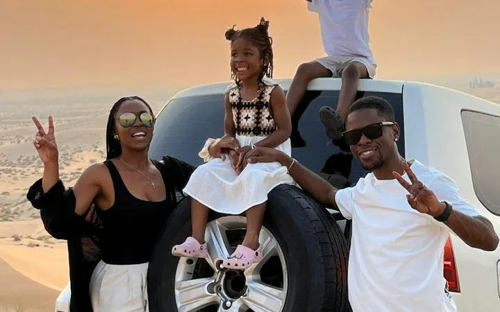 Family posing on SUV in Abu Dhabi desert during safari tour with dune bashing and camel ride.