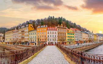 Karlovy Vary colorful buildings along river at sunset, view from bridge, self-guided tour.