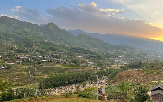 Sapa rice fields and villages with mountain backdrop during motorbike tour.