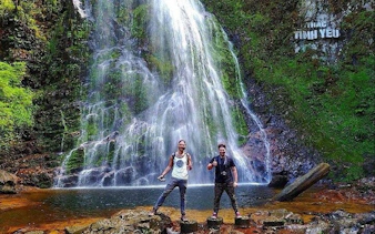 Visitors at Love Waterfall in Sapa, Vietnam, standing on rocks with cascading water in the background.
