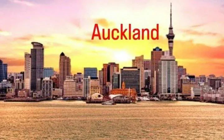 Auckland skyline with Sky Tower at sunset, viewed from the harbor.
