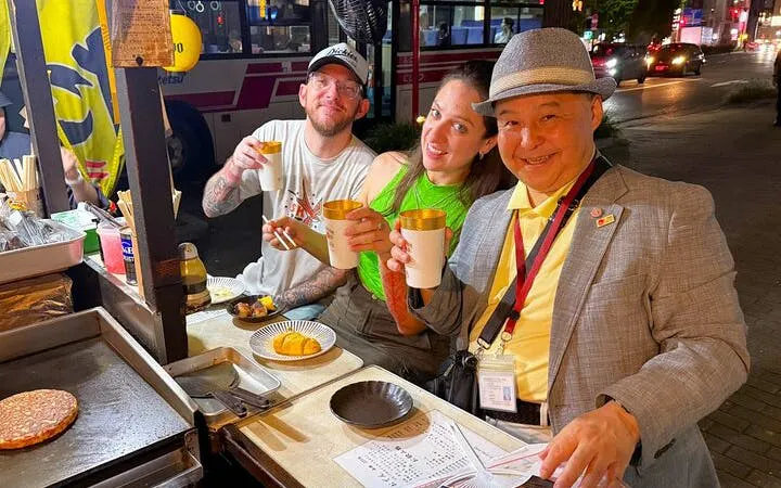 Nakasu food stall tour in Fukuoka with guide and tourists enjoying local dishes.