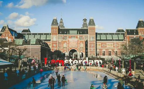 Amsterdam Rijksmuseum with ice rink and "I amsterdam" sign, part of guided city tour.
