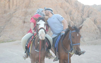 Couple horse riding in Sharm El Sheikh desert with rocky landscape.