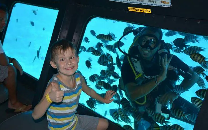 Child inside semi-submarine viewing diver and fish in Hurghada sea trip.