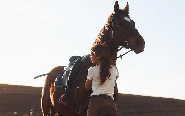 Horseback rider preparing horse in Hurghada desert for Red Sea tour.