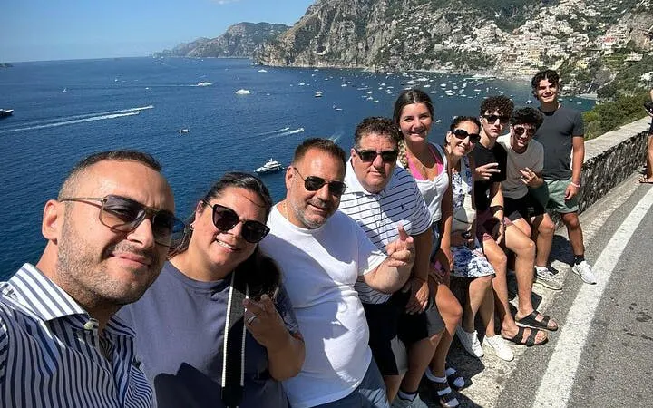 Small group enjoying scenic view of Amalfi Coast with cliffs and sea in the background.