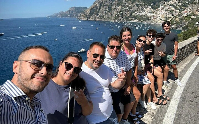 Small group enjoying scenic view of Amalfi Coast with cliffs and sea in the background.