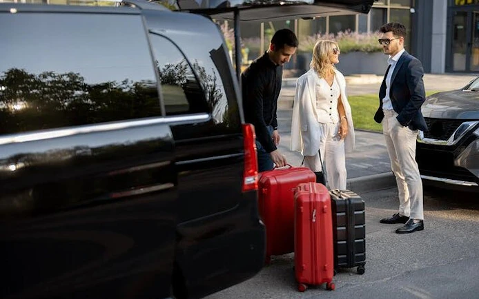 Travelers with luggage beside a private transfer vehicle in Agadir for Marrakesh journey.