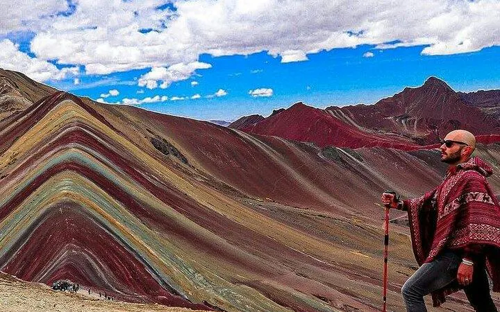 Rainbow Mountain view with a person in traditional attire, Cusco tour.