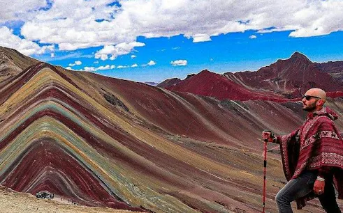 Rainbow Mountain view with a person in traditional attire, Cusco tour.