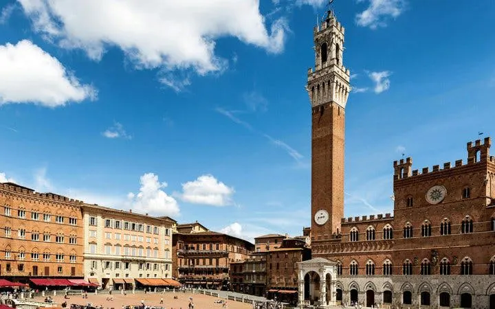 Siena's Piazza del Campo with Torre del Mangia under a blue sky.