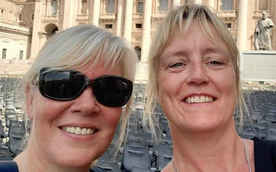 Two people smiling in front of St. Peter's Basilica, Rome, during a city exploration game.