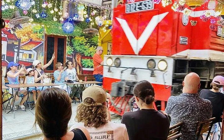 Tourists watch a train pass by at Hanoi's Train Street during a cyclo tour in the Old Quarter.