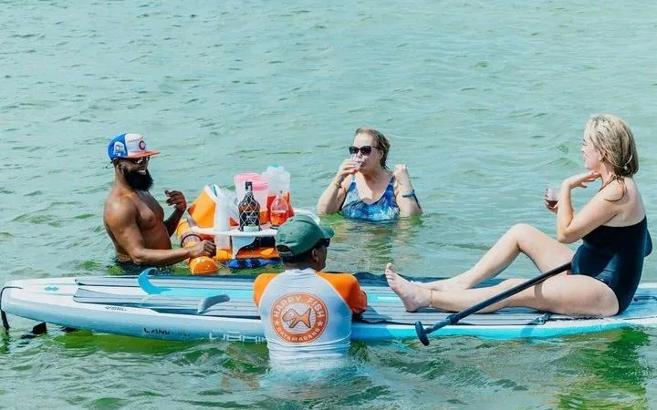 Group enjoying drinks on a floating table in Punta Cana during a catamaran snorkeling cruise.